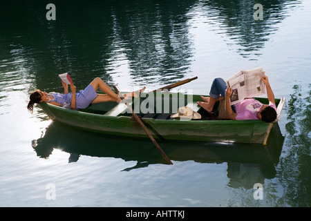 Man and woman lying down and reading in a boat Stock Photo