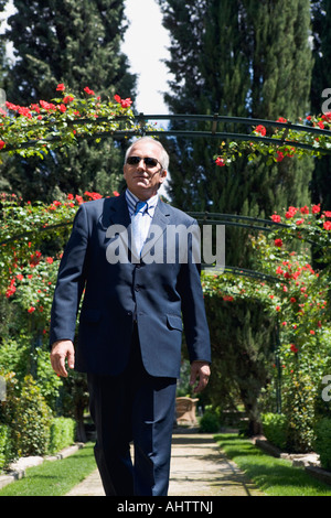 Businessman walking through leafy gardens Stock Photo