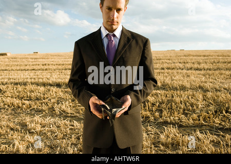 Man holding empty wallet in wheat field. Stock Photo