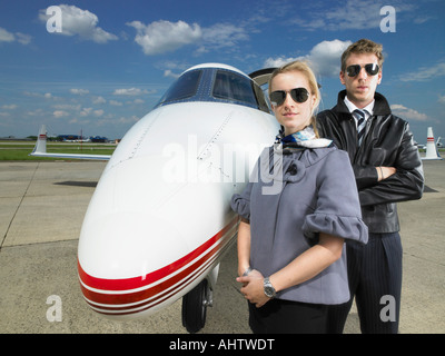 Pilot and flight attendant standing in front of private jet. Stock Photo