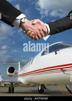 Two people shaking hands in front of private jet. Stock Photo