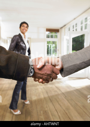 Shake hands in front of smiling woman in an empty house. Close up. Stock Photo