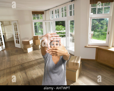 Women framing face while moving into empty house. Stock Photo
