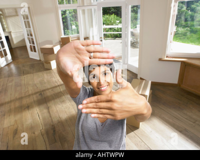 Woman framing face with hands moving into empty house. Stock Photo
