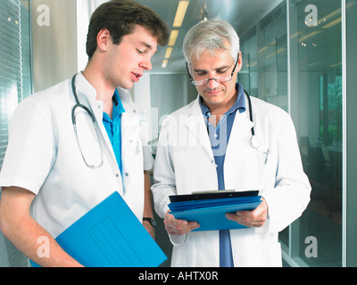 Mature doctor and young doctor in discussion in a lobby of a hospital. Stock Photo
