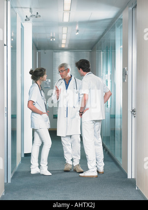 Three doctors in discussion in hospital lobby. Stock Photo