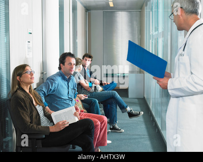 Male doctor calling for patients in hospital waiting room. Stock Photo