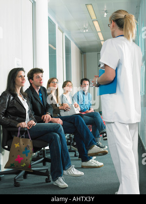 Female doctor calling next patient in hospital waiting room. Stock Photo