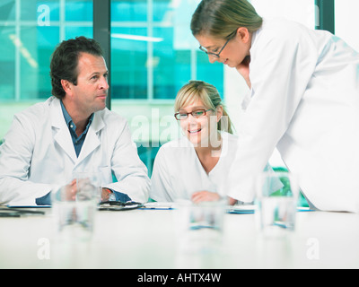 Three doctors smiling and talking in a meeting. Stock Photo