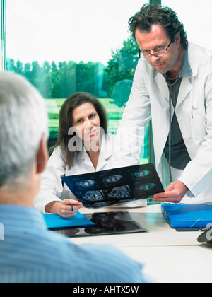 Two doctors in discussion with mature male patient. Stock Photo