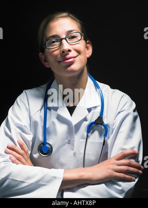 Portrait of smiling female doctor at her desk working late looking at camera. Stock Photo