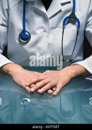 Close up of hands of female doctor at her desk carrying a stethoscope. Stock Photo