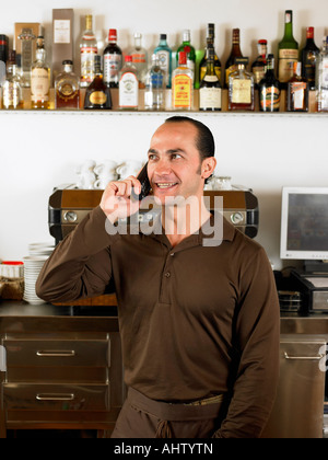 Bartender on the phone in front of coffee machine. Stock Photo