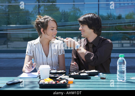 Couple eating sushi together outside while working. Stock Photo
