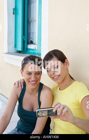Two young girls outside a Greek House taking a self portrait with mobile smiling Stock Photo