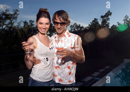 A couple drinking cocktails by a pool Stock Photo