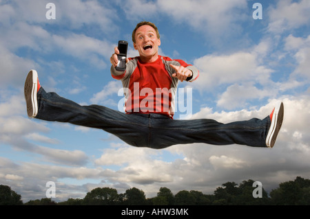 Man jumping in the air holding his cell phone Stock Photo