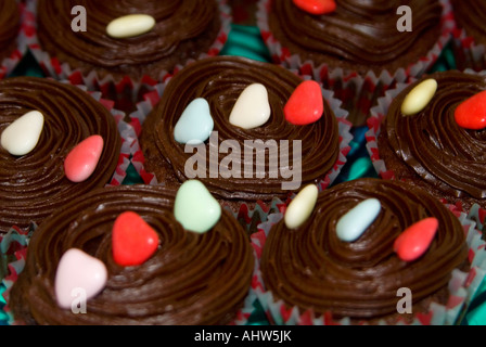 Horizontal close up of several homemade chocolate fairy cakes, aka cupcakes, decorated with sugar hearts. Stock Photo