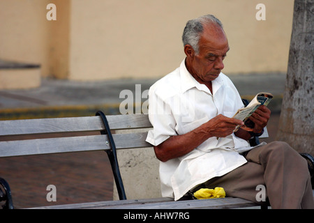 Retired old man spending time outdoors reading a magazine in a park at Panama City Stock Photo