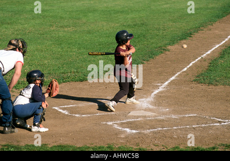 Little league action the batter hits the ball Stock Photo