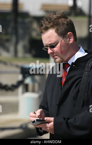 The man manager standing in front of an office building on the city street with PDA Personal Data Assistant in USA US vertical hi-res Stock Photo