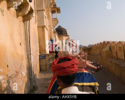 Amber Jaipur Tourists riding elephant taxis to Amber Fort from elephant seat looking over mahout's red turban Stock Photo