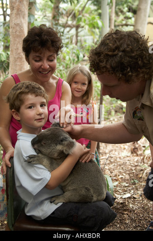 Young boy child holding a Koala bear in Lone Pine Koala Sanctuary wildlife reserve zoo Brisbane Queensland QLD Australia NAOH Stock Photo