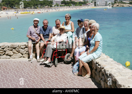 Old aged pensioners elderly aged mature posing for photos at the beach Majorca in summer Stock Photo