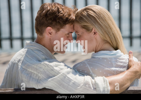 Couple hugging in a park seated in a bench Stock Photo - Alamy