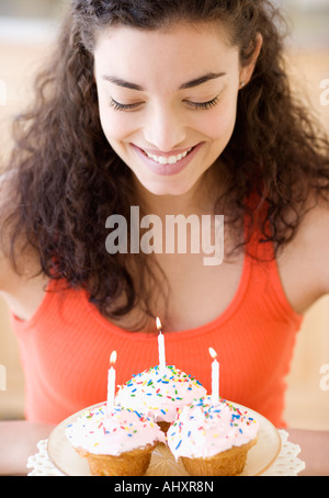 Woman holding plate of cupcakes with candles Stock Photo