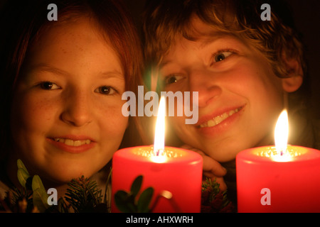 portrait of a young girl and a young boy looking at the burning candles of an Advent wreath happily Stock Photo