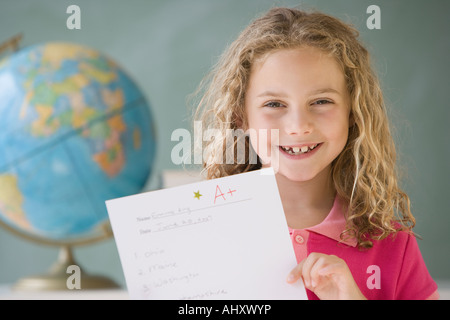 Girl holding up A plus paper in classroom Stock Photo