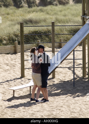 Couple dancing together in a children's playground beside the beach. Stock Photo