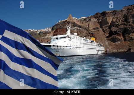 The Greek flag flies in front of the cruise ship Spirit of Adventure, moored in Santorini, Greece Stock Photo