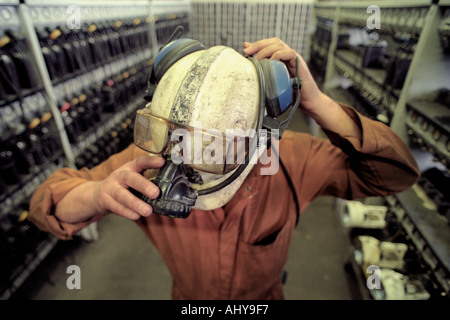 A miner puts on his hard hat and light in the lamp room of Tower Colliery deep coal mine at Hirwaun South Wales Stock Photo