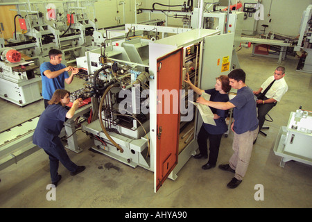 Trainees with an instructor working with cylinder head stud runner on a production line at training centre in South Wales UK Stock Photo