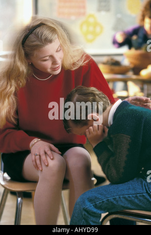 Caucasian teacher talking to troubled male student in elementary school classroom Stock Photo