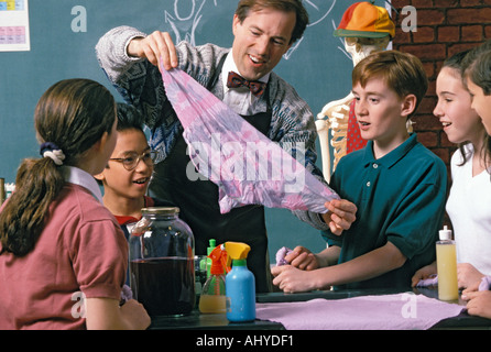 Caucasian science teacher demonstrating scientific concept to Asian American and Caucasian middle school students Stock Photo