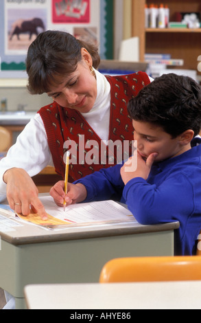 Caucasian teacher helping student in elementary school classroom vertical Stock Photo