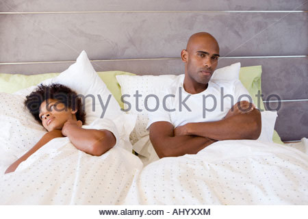 young-couple-in-bed-man-sitting-up-with-arms-crossed-portrait-ahyxxm.jpg