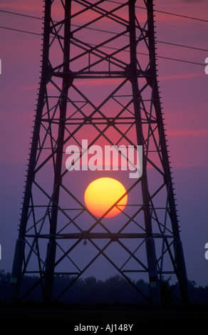 orange sun setting behind a pylon Stock Photo