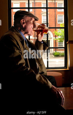 Old man drinking pint of beer in pub UK Stock Photo