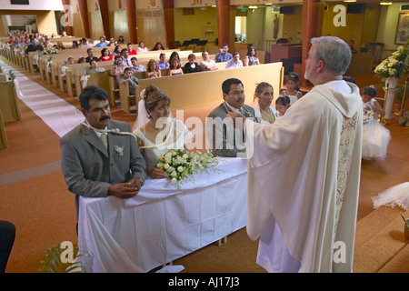 Catholic Priest administers wedding vows to two Latino American couples at St Thomas Catholic Church in Ojai California Stock Photo