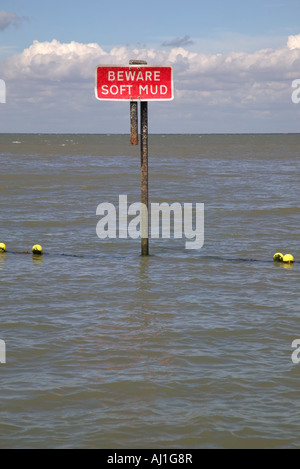 Beware soft mud signpost in the sea Stock Photo
