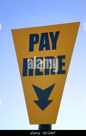 Pay here yellow sign against a blue sky