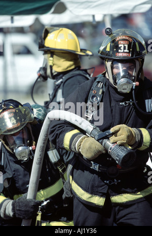 Three fire fighters holding a hoseline getting ready to use it on a fire at a scene Stock Photo