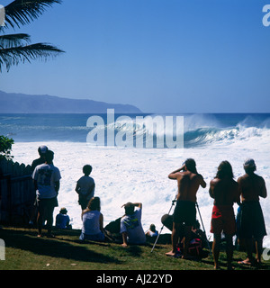 Group of spectators watching surfers on huge breaking wave at Waimea Bay North Shore Oahu Island Hawaii Stock Photo