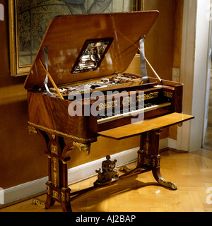 Antique square piano with open lid beneath gilt framed artwork Stock Photo