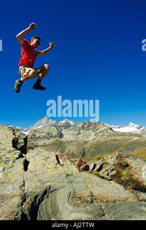 Hiker jumping high on trails at Schwarzee Paradise (MR), Zermatt, Valais, Switzerland. Stock Photo