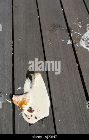Melting and broken ice cream cone on seaside wooden pier Stock Photo